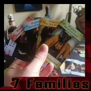 Hand holding several 7 Families cards by Cyb, gothic art and digital vanitas..