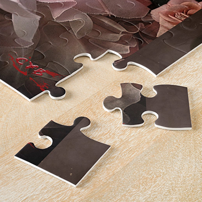 Gros plan sur les pièces épaisses d’un puzzle artistique de Cyb, disposées sur une table en bois clair.